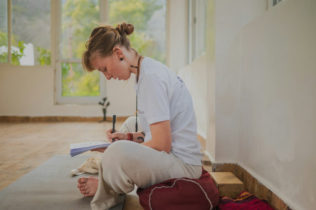 Brazilian woman writing notes at a wooden desk near a window